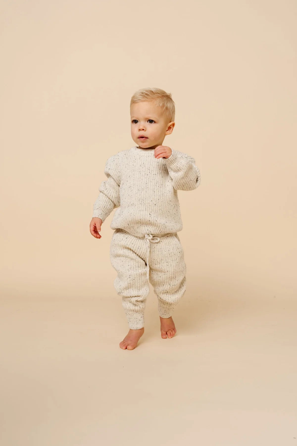 Toddler wearing cream speckle knit chunky sweater and matching jogger pants, cozy two-piece set.