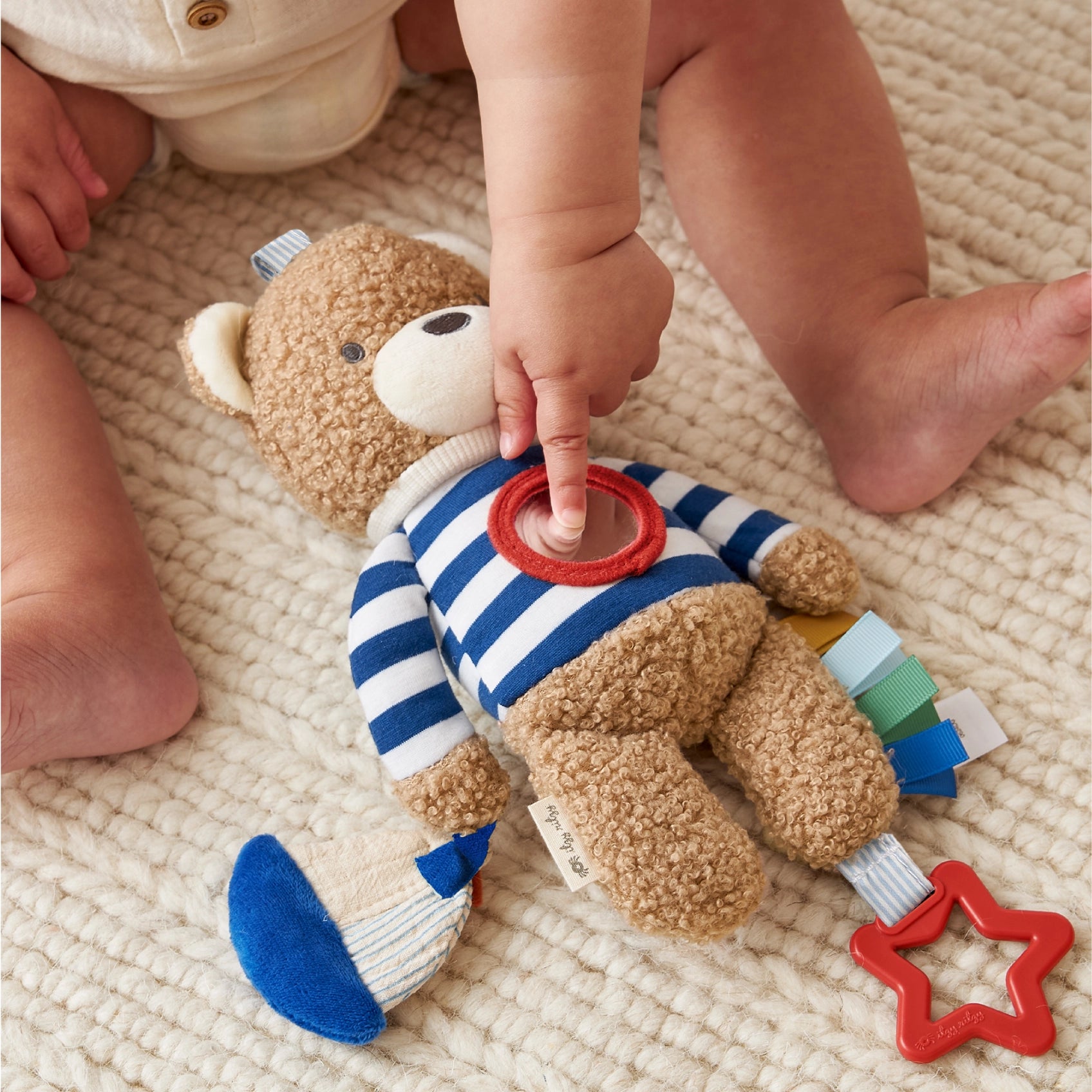 Child's hand interacting with a teddy bear toy on a textured surface