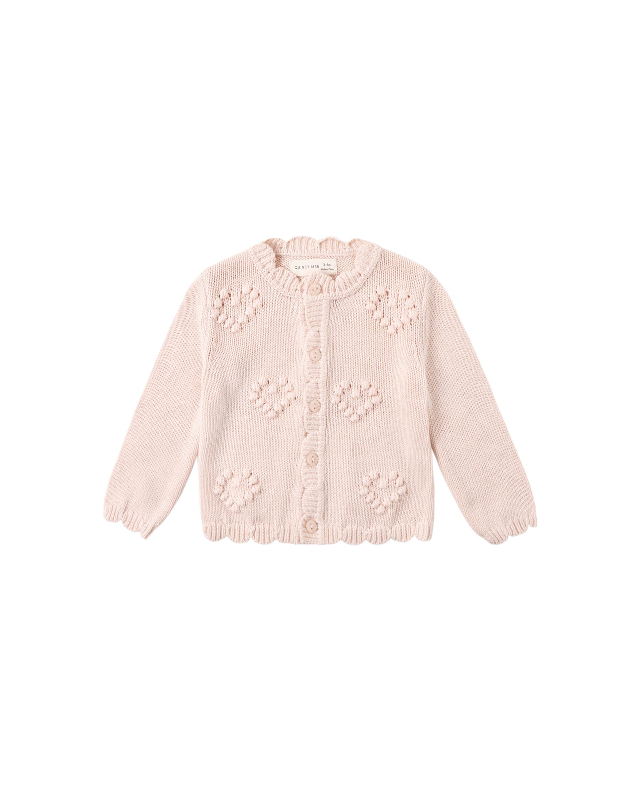 Pink knitted cardigan with floral patterns on a white background
