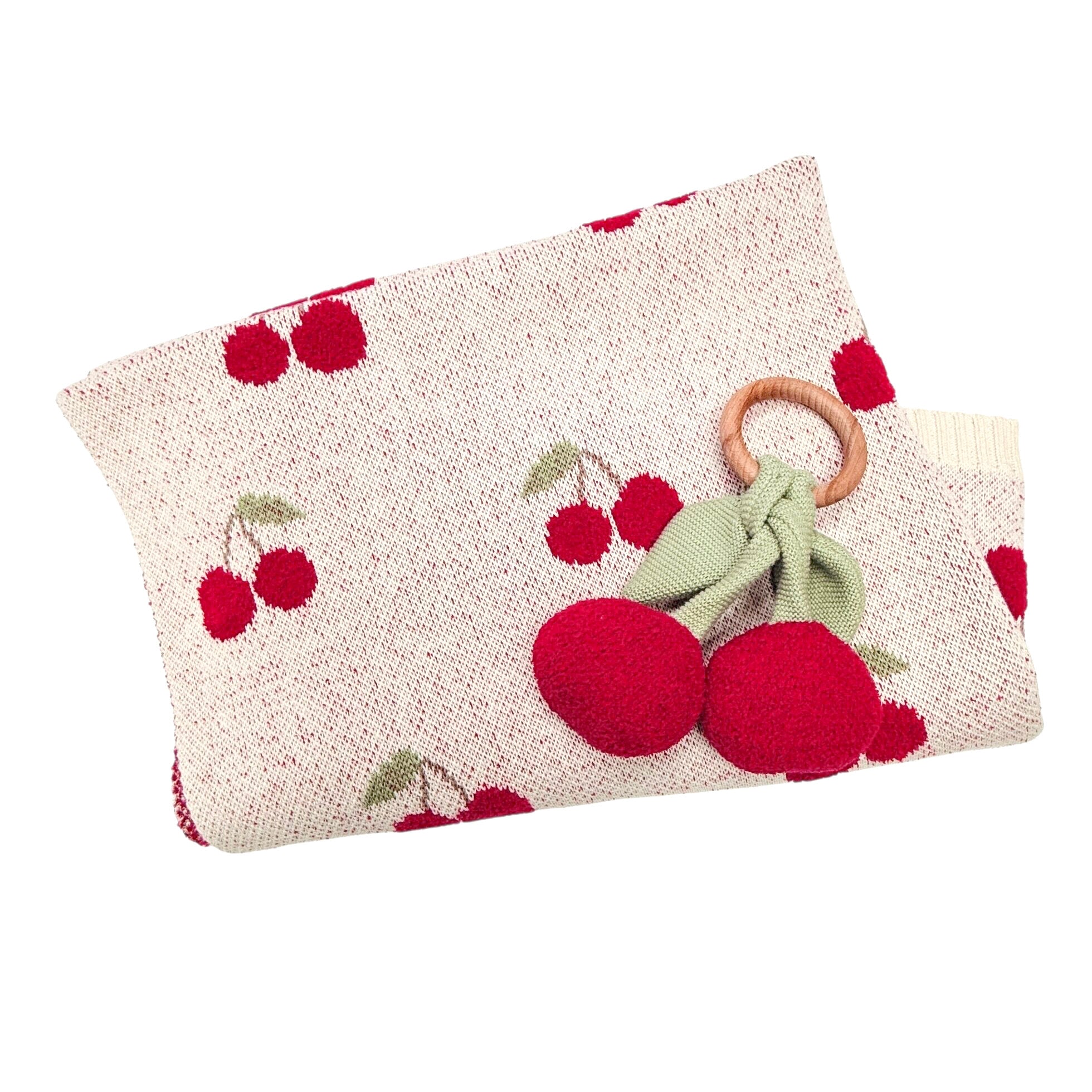 Knitted blanket with cherry pattern and wooden ring cherry teether on a white background
