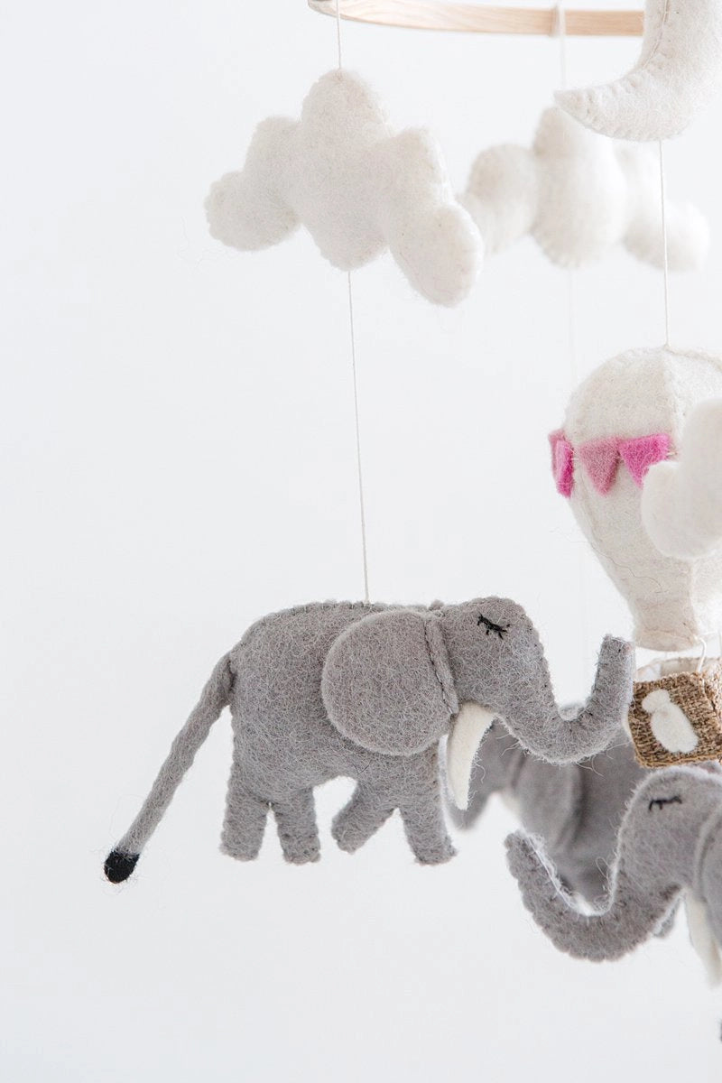 Plush elephant mobile hanging against a white background
