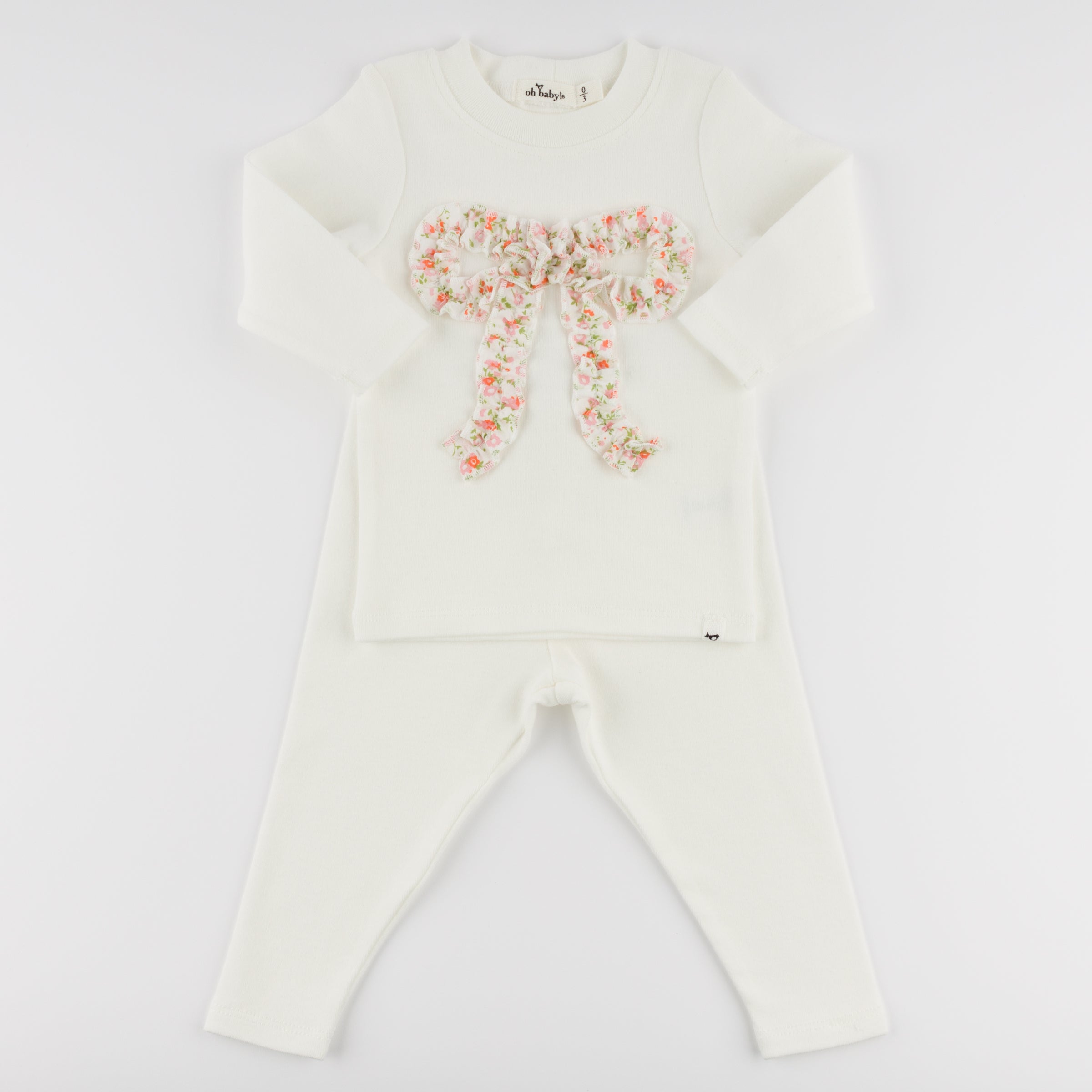 White outfit with floral bow design on a light gray background