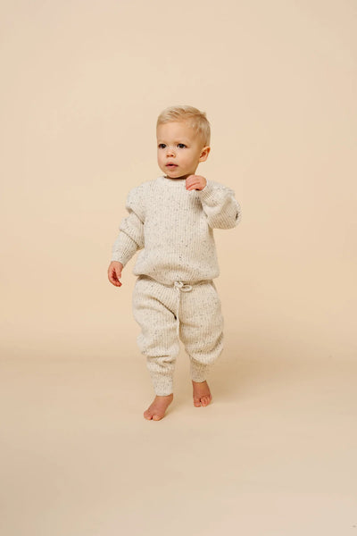 Toddler wearing cream speckle knit chunky sweater and matching jogger pants, cozy two-piece set.