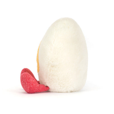 White textured egg with a red heart-shaped item on a white background