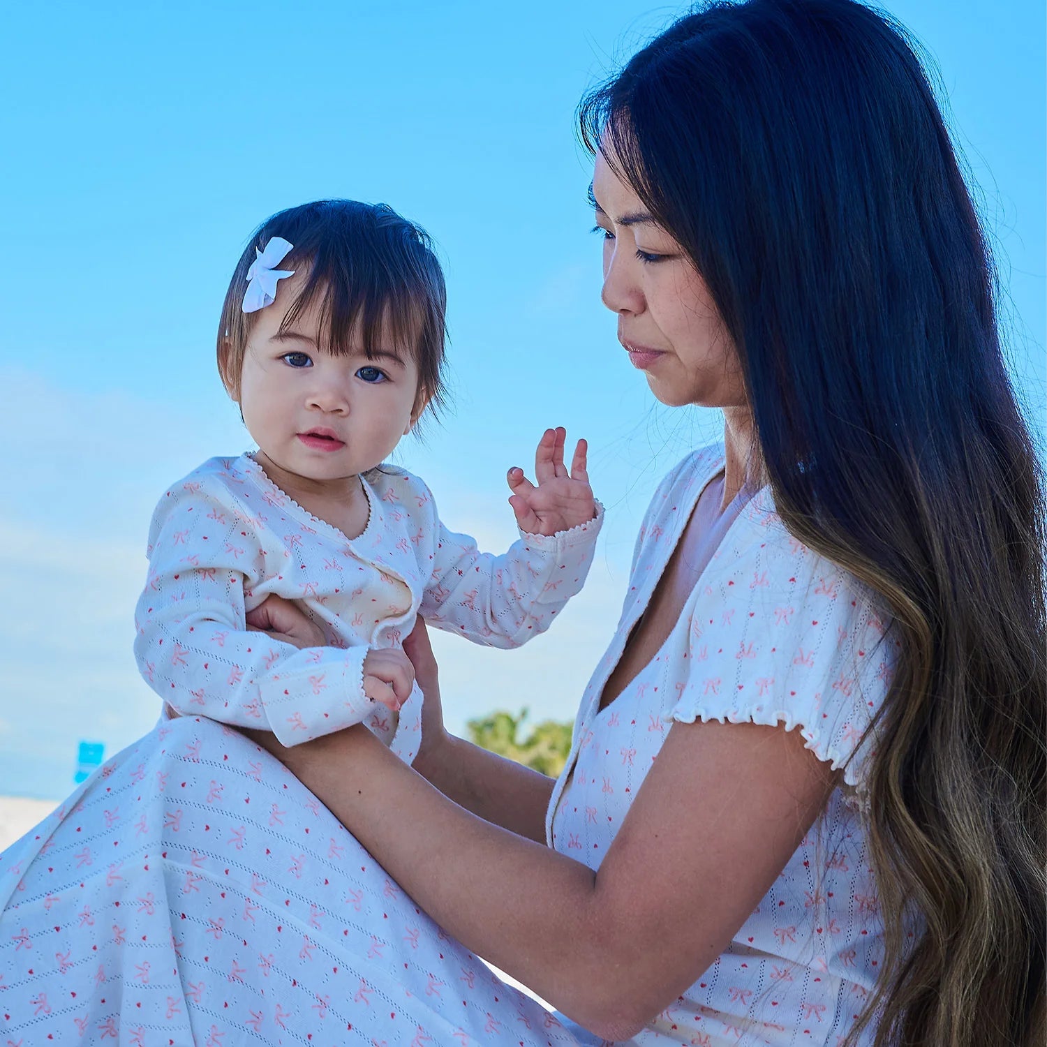 Woman holding a baby with a clear blue sky in the background