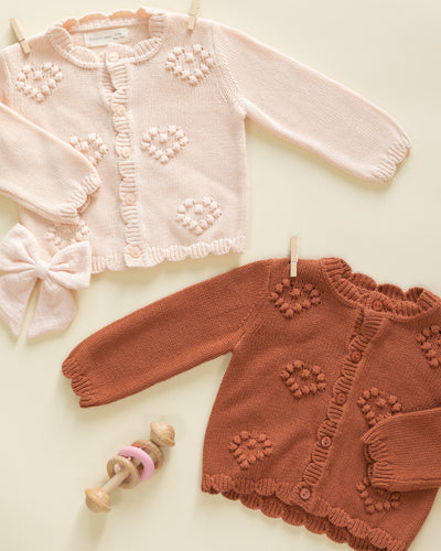Two knitted sweaters, one pink and one brown, on a light background.