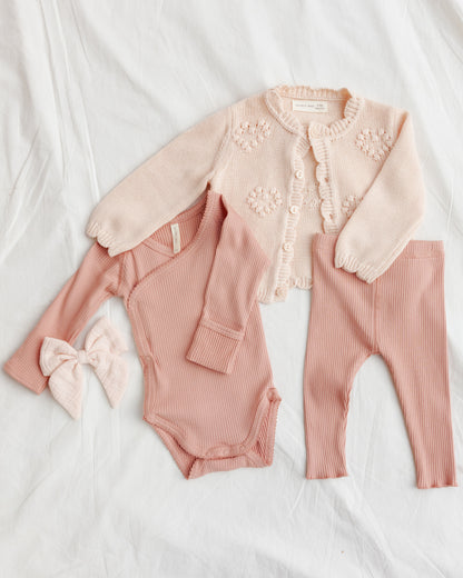 Pink baby outfit with cardigan on a white background
