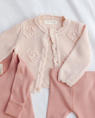 Pink baby outfit with a knitted cardigan on a white background