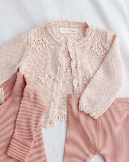 Pink baby outfit with a knitted cardigan on a white background