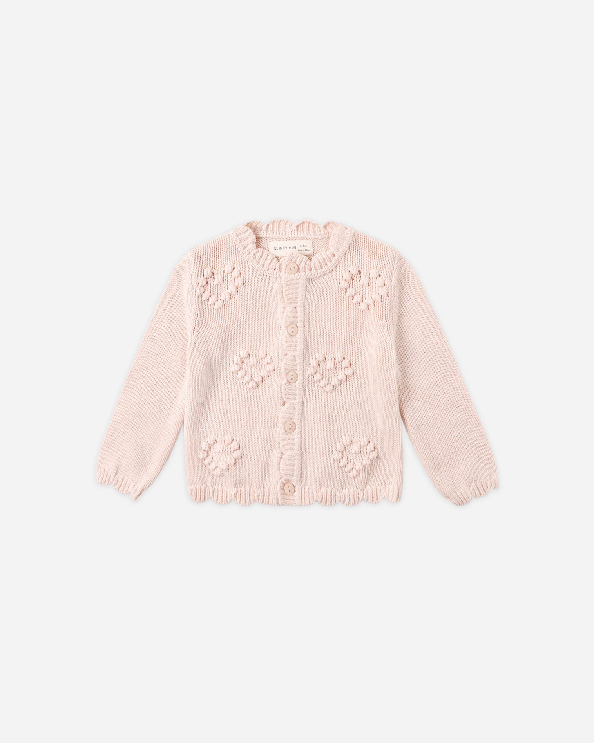 Pink knitted cardigan with floral patterns on a white background