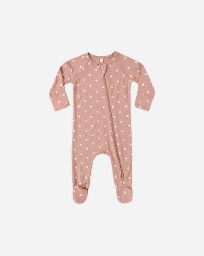 Pink baby onesie with white patterns on a light beige background