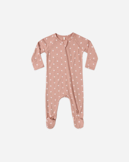 Pink baby onesie with white patterns on a light beige background
