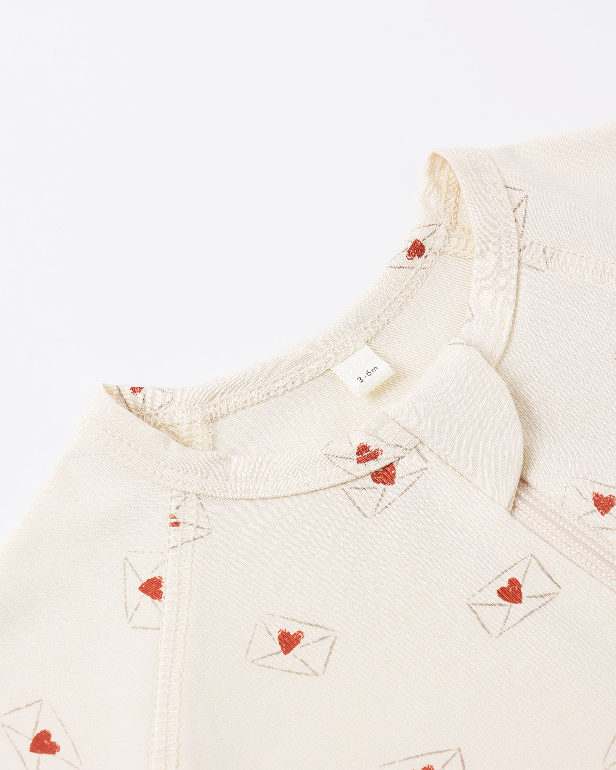 Close-up of a cream-colored garment with red heart designs on a white background