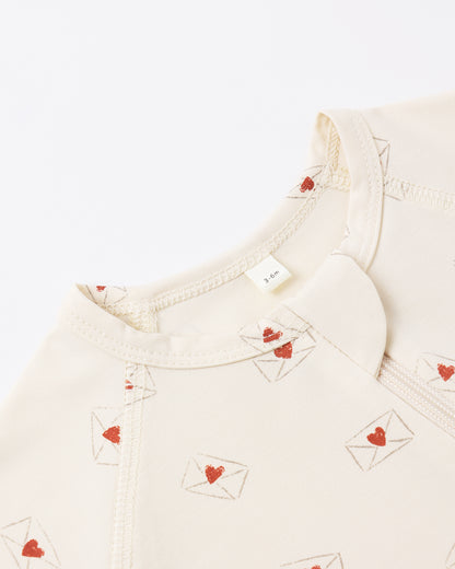 Close-up of a cream-colored garment with red heart designs on a white background