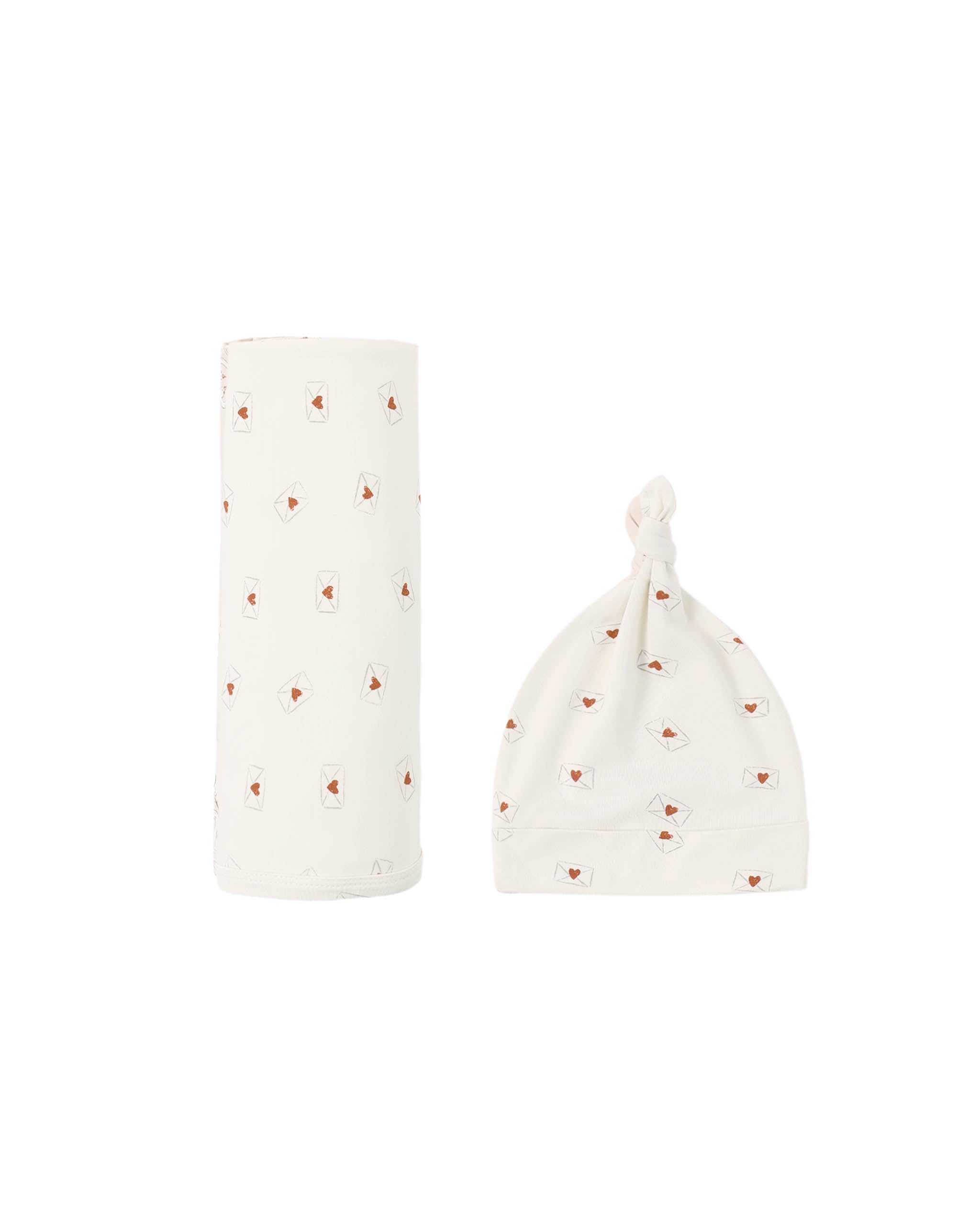 Baby hat and bottle cover with heart pattern on a white background