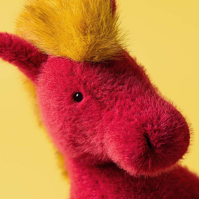 Close-up of a pink and yellow plush toy on a yellow background