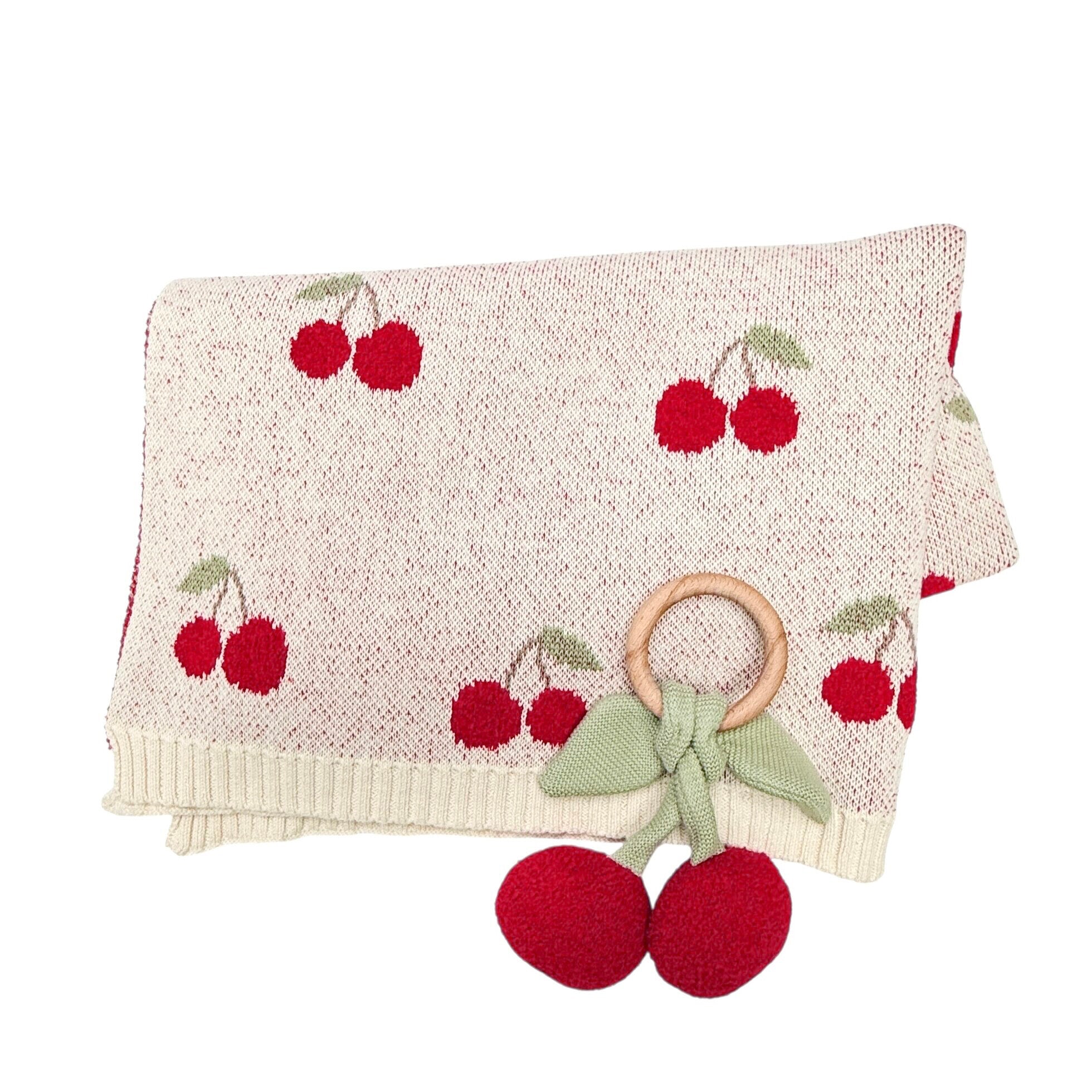 Baby blanket with cherry pattern and matching rattle on a white background
