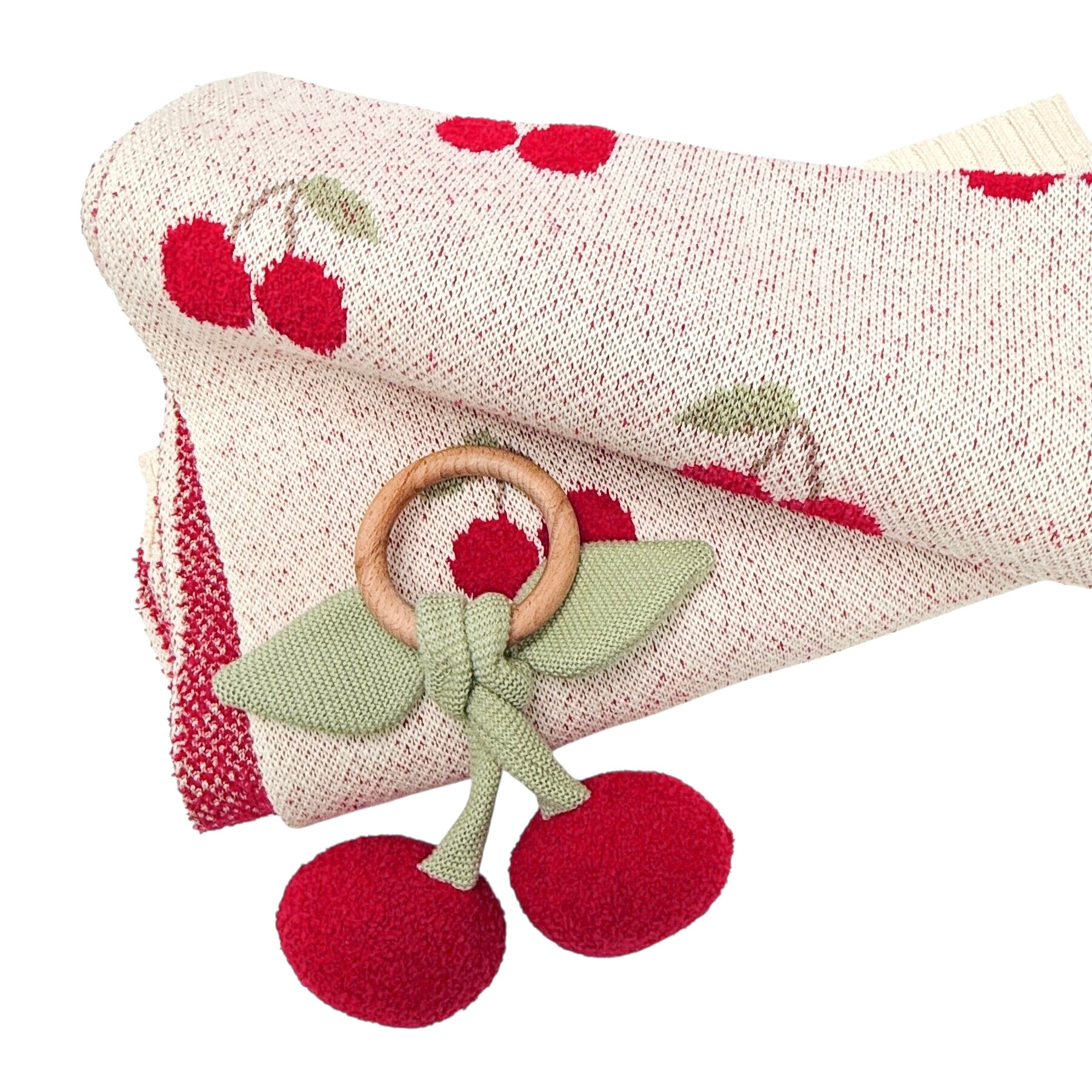 Wooden teething ring with red fabric and green bow on a textured fabric background