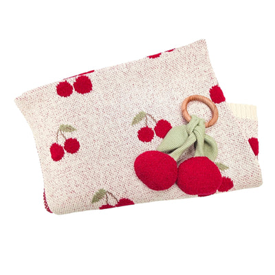 Knitted blanket with cherry pattern and wooden ring cherry teether on a white background