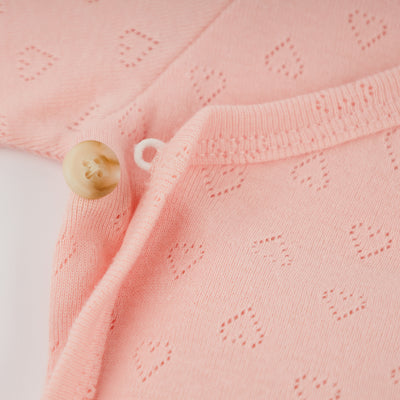 Close-up of a pink fabric with a button on a light pink background