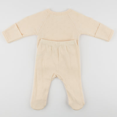 Beige baby onesie with long sleeves and legs on a light gray background