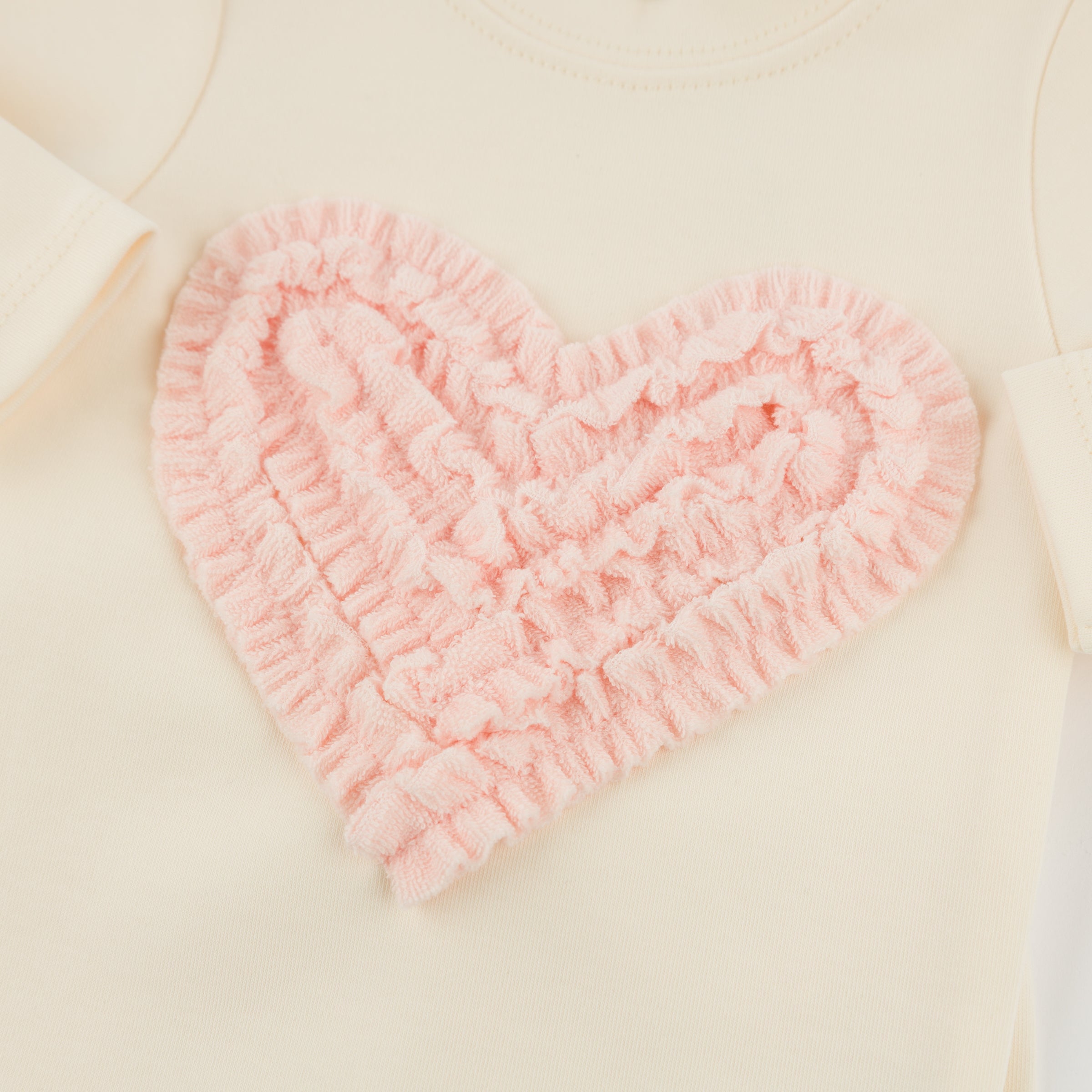 Pink heart-shaped bath mat on a beige surface